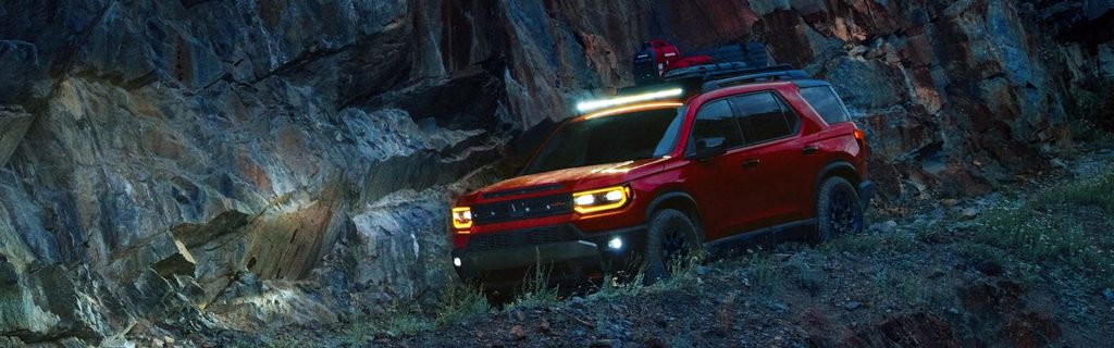 Red Honda Passport off-roading at night.