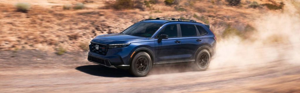 2026 Honda CR-V driving on a dusty road with rugged terrain