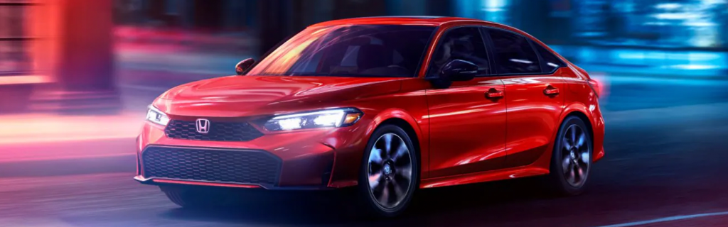 Red Honda Civic sedan driving through a city at night, highlighting its sporty design and modern styling.