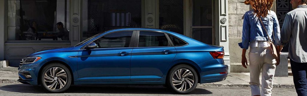 Blue Volkswagen Jetta sedan parked along a city street, showcasing its sleek design and refined everyday style.