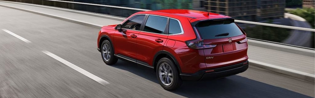 Red Honda CR-V driving on a city highway, showcasing its sleek design and everyday versatility.